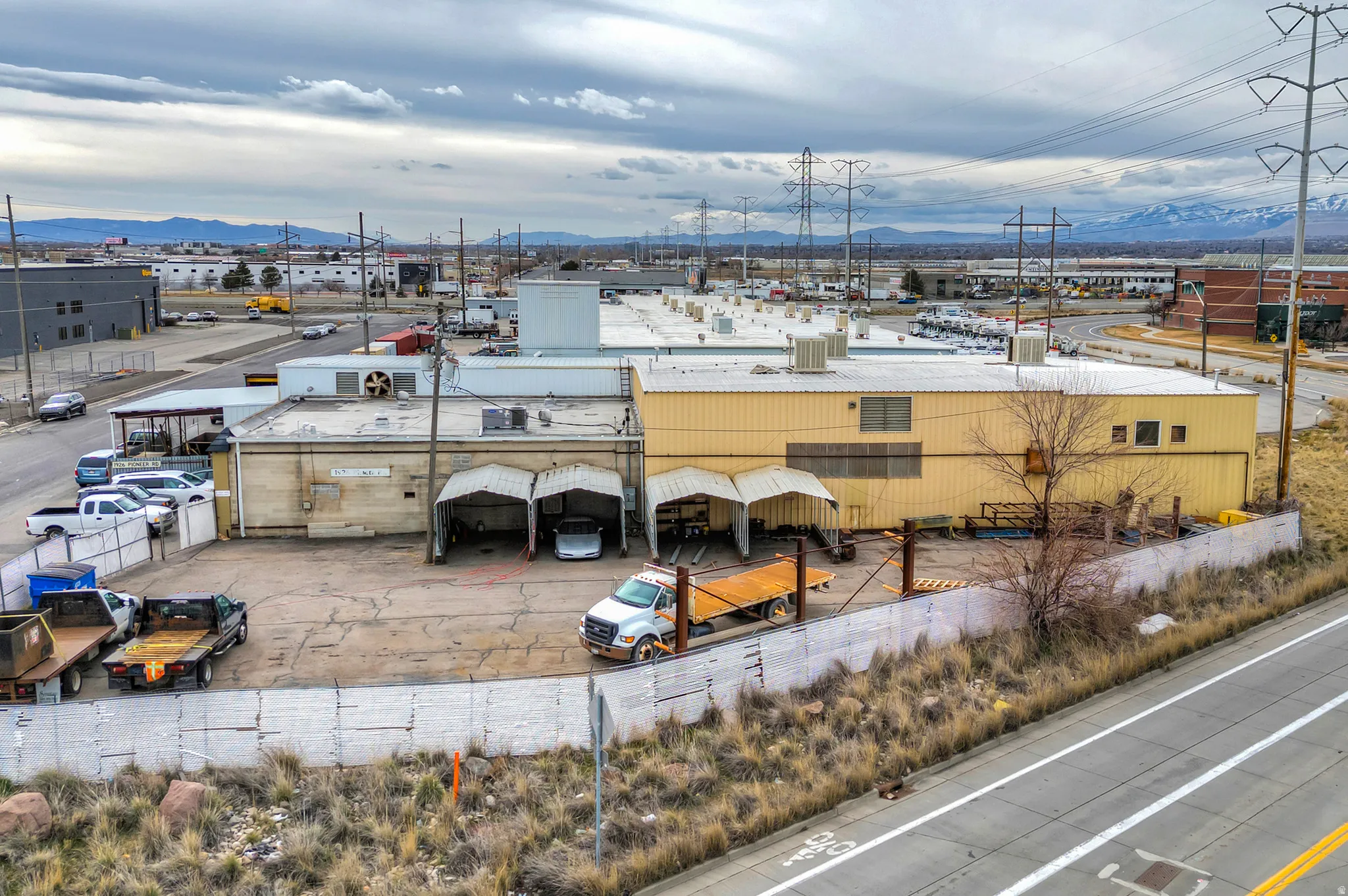 Industrial building with multiple bay entrances, extensive paved lot, and a metal perimeter fence
