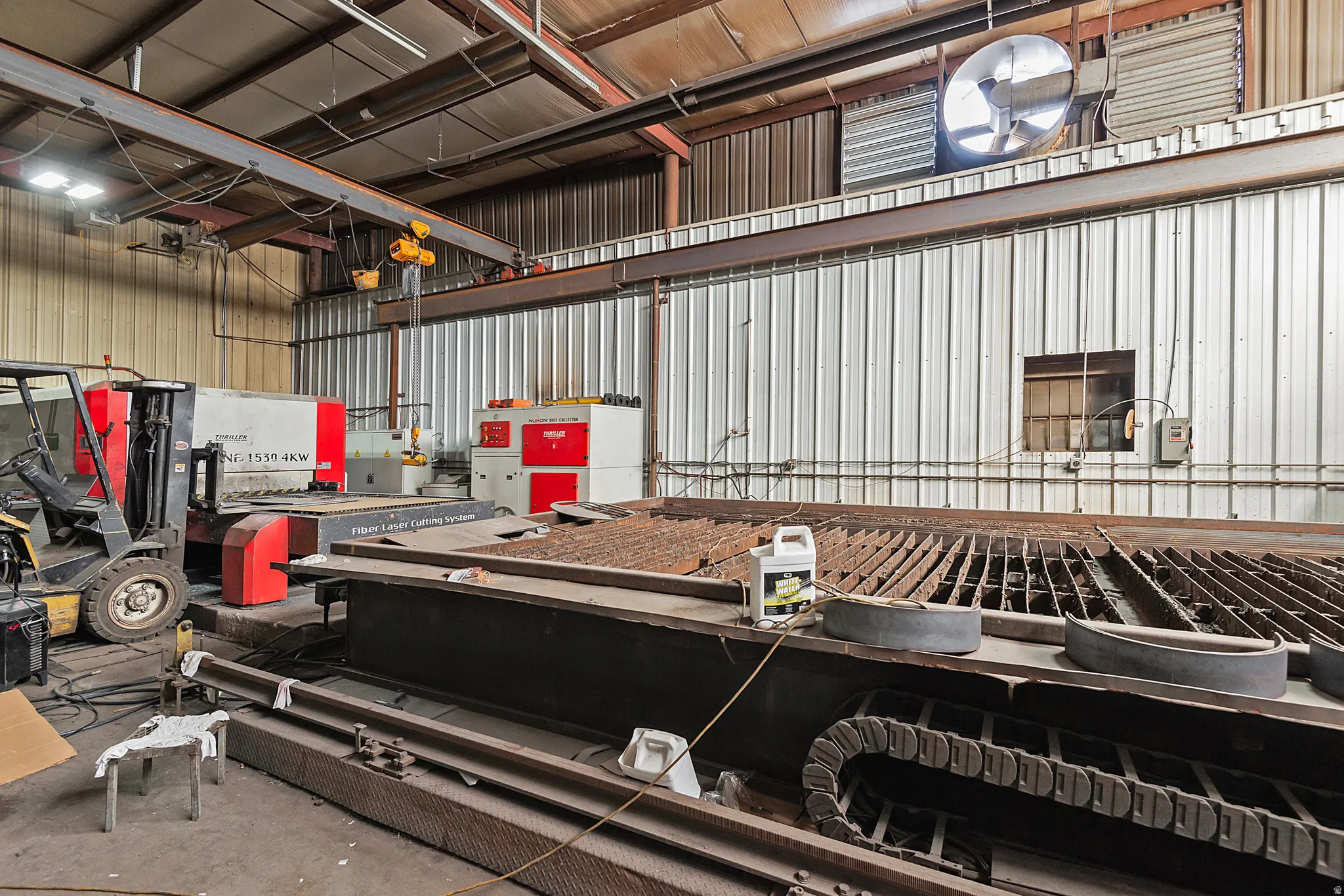 Industrial space featuring metal wall panels, overhead lighting, and a large overhead crane system