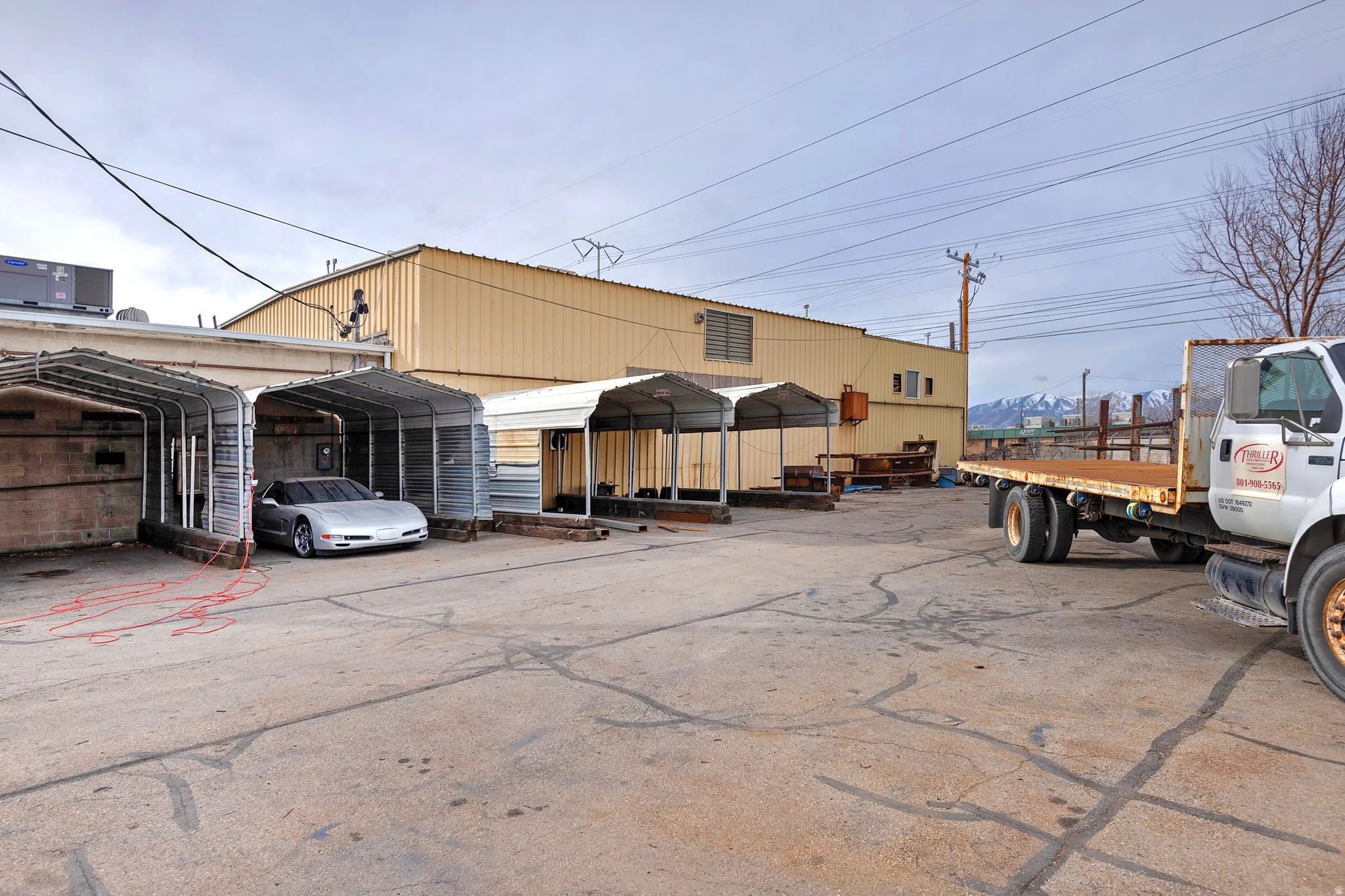 Paved lot with multiple covered parking structures and a large industrial building