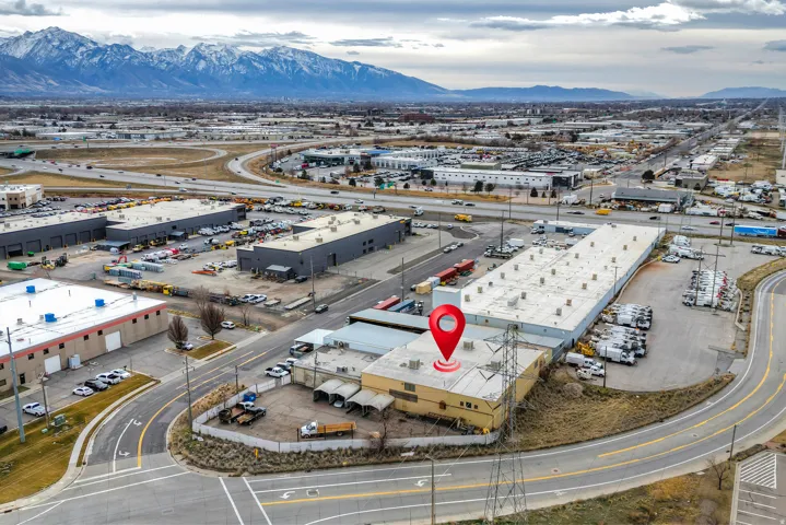 Commercial property with extensive paved parking, direct road access, and mountain backdrop
