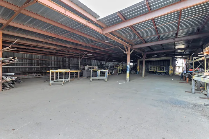 Open-air warehouse featuring a corrugated metal roof and exposed steel beam construction