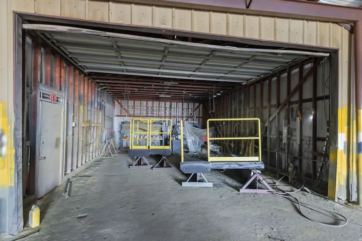 Open warehouse space with a concrete floor, metal beam ceiling, and exposed wall studs
