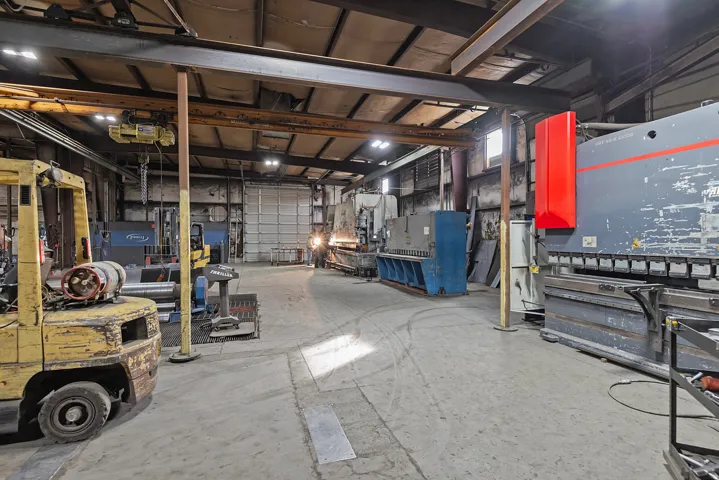 Warehouse interior featuring a concrete floor, exposed structural beams, and a large roll-up door