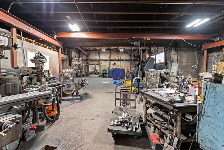 Industrial-style interior featuring exposed structural beams, concrete flooring, and ample overhead lighting