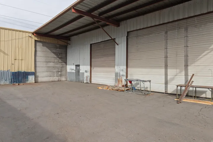 Metal construction with multiple roll-up doors, covered exterior areas, and a concrete lot