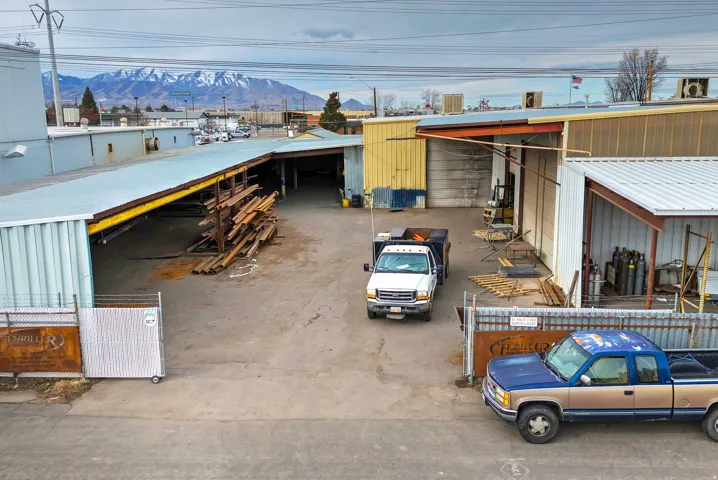 Industrial structures featuring metal siding and roofing, multiple open bays, and a large paved lot