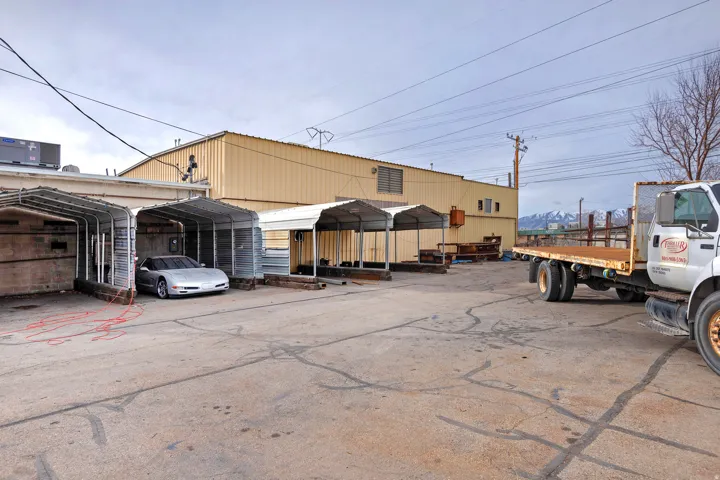 Paved lot with multiple covered parking structures and a large industrial building