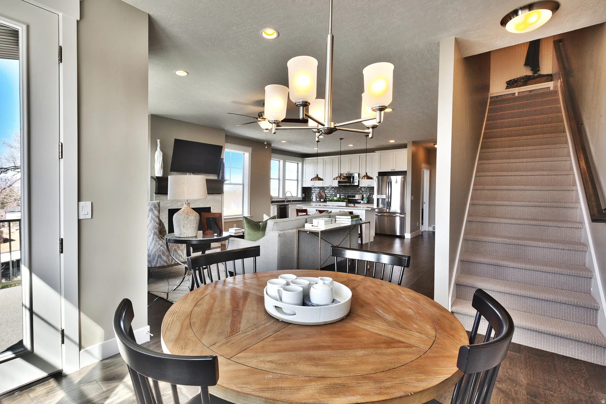 Open-concept living space featuring wood-finish flooring, a contemporary chandelier, and a carpeted staircase