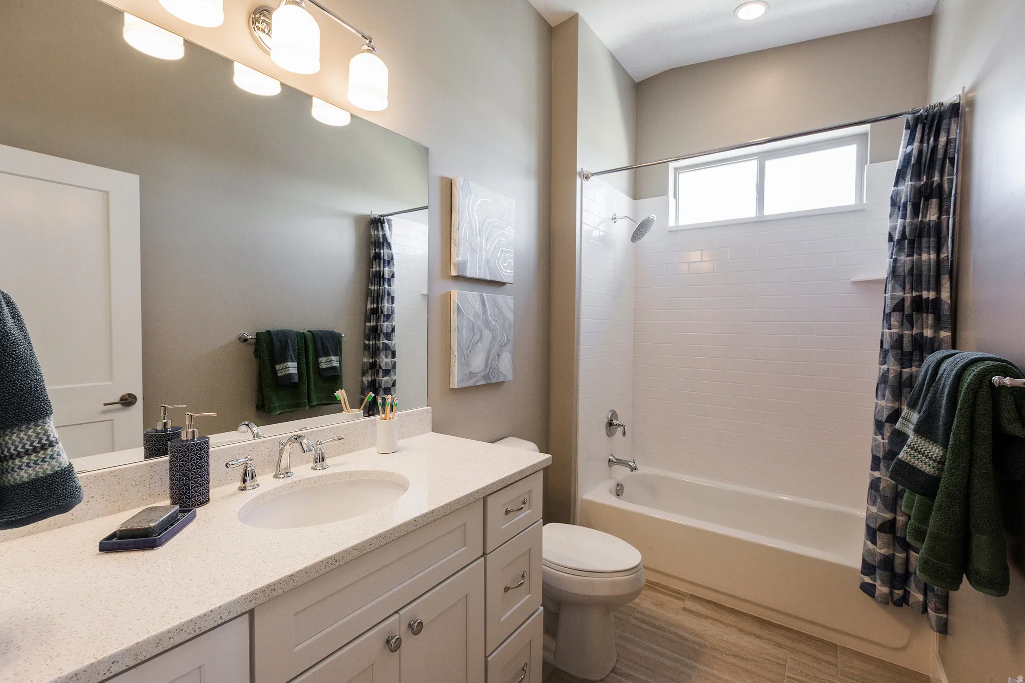 Bathroom featuring a single vanity with an integrated sink, polished chrome faucet, and recessed lighting