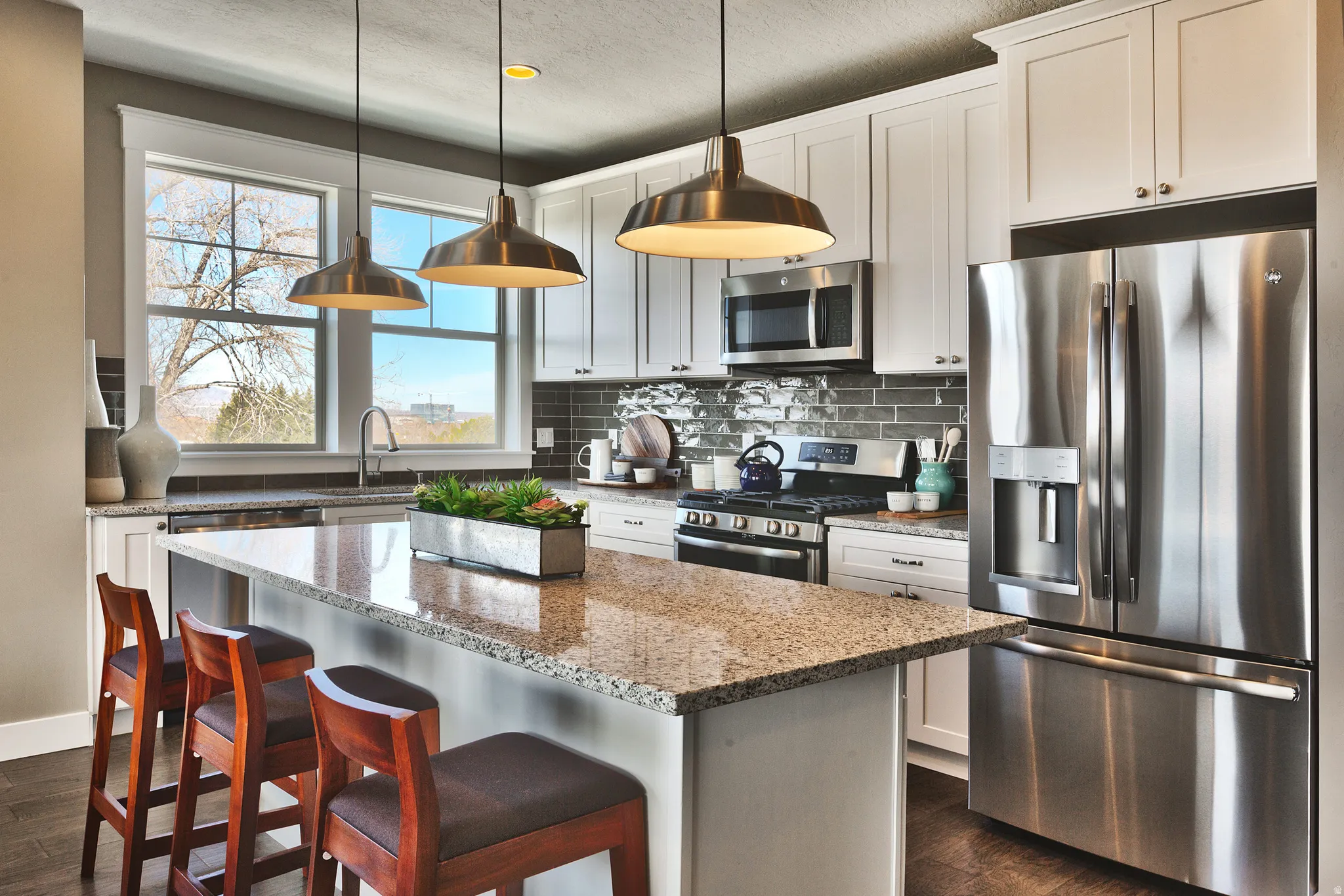 Contemporary kitchen featuring white cabinetry, stainless steel appliances, a tile backsplash, granite countertops, and pendant lighting