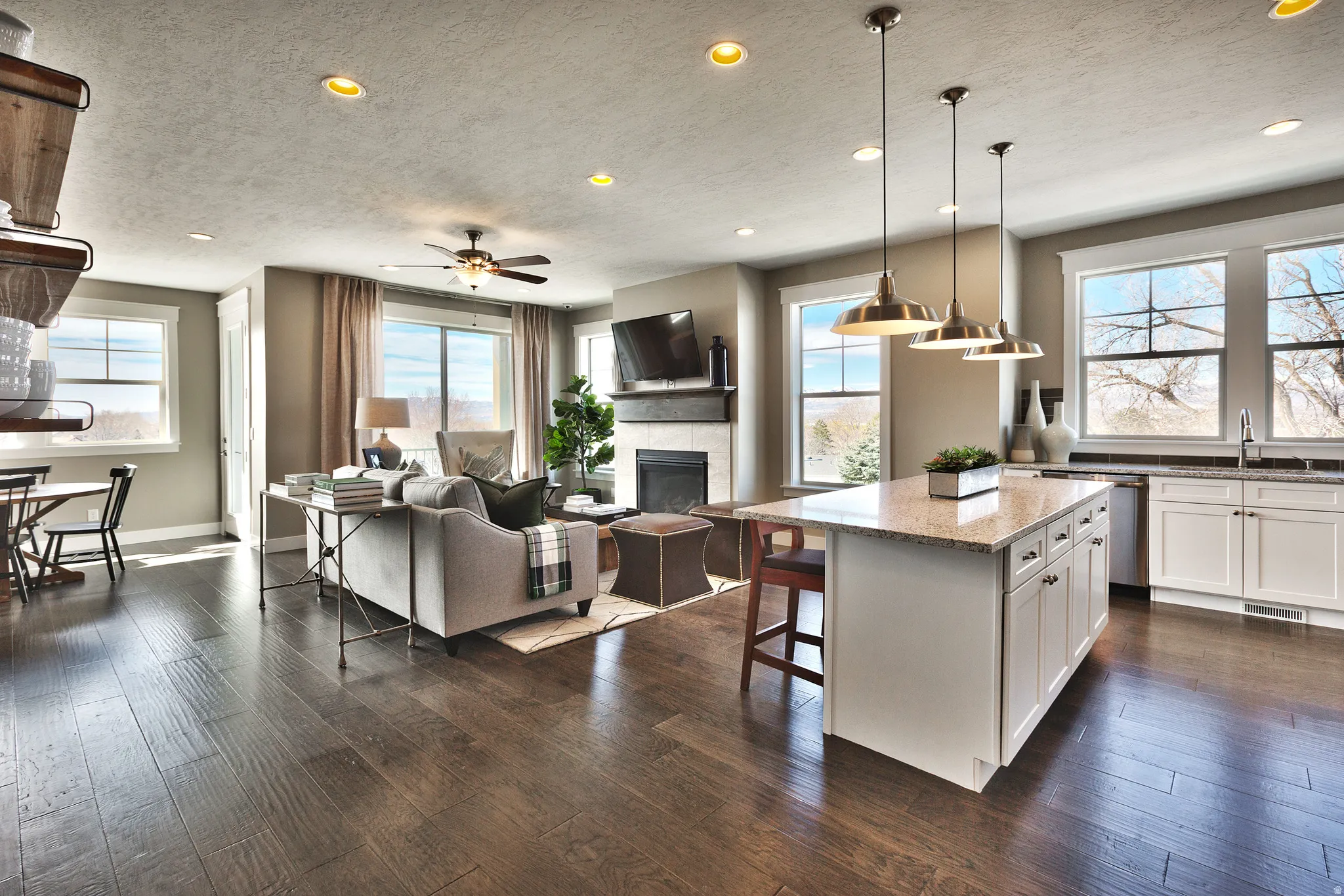 Open-concept living space featuring wood-finish flooring, a kitchen island with seating, a built-in fireplace, and recessed lighting