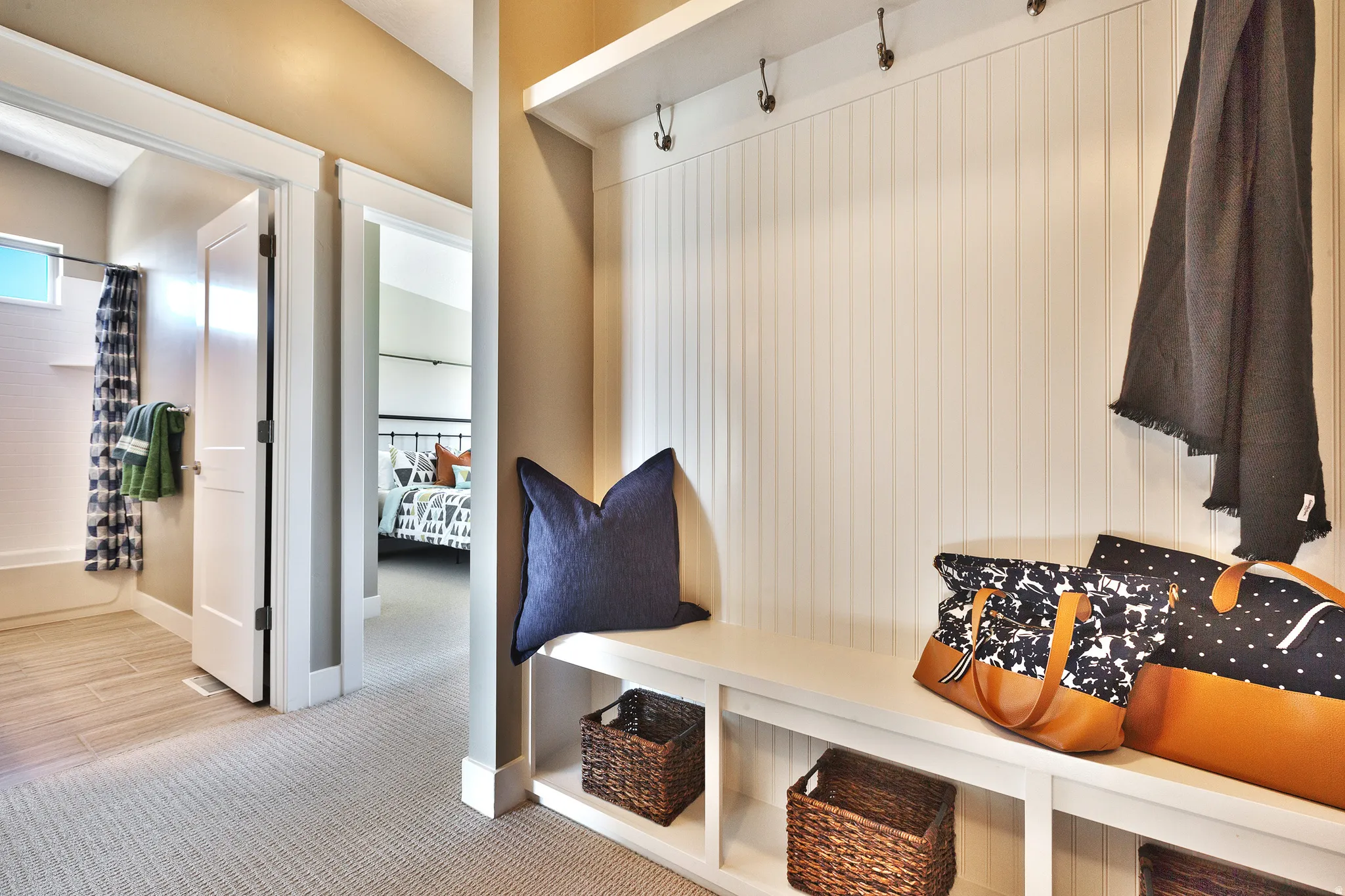 Built-in bench with storage, beadboard paneling, and an upper shelf with coat hooks