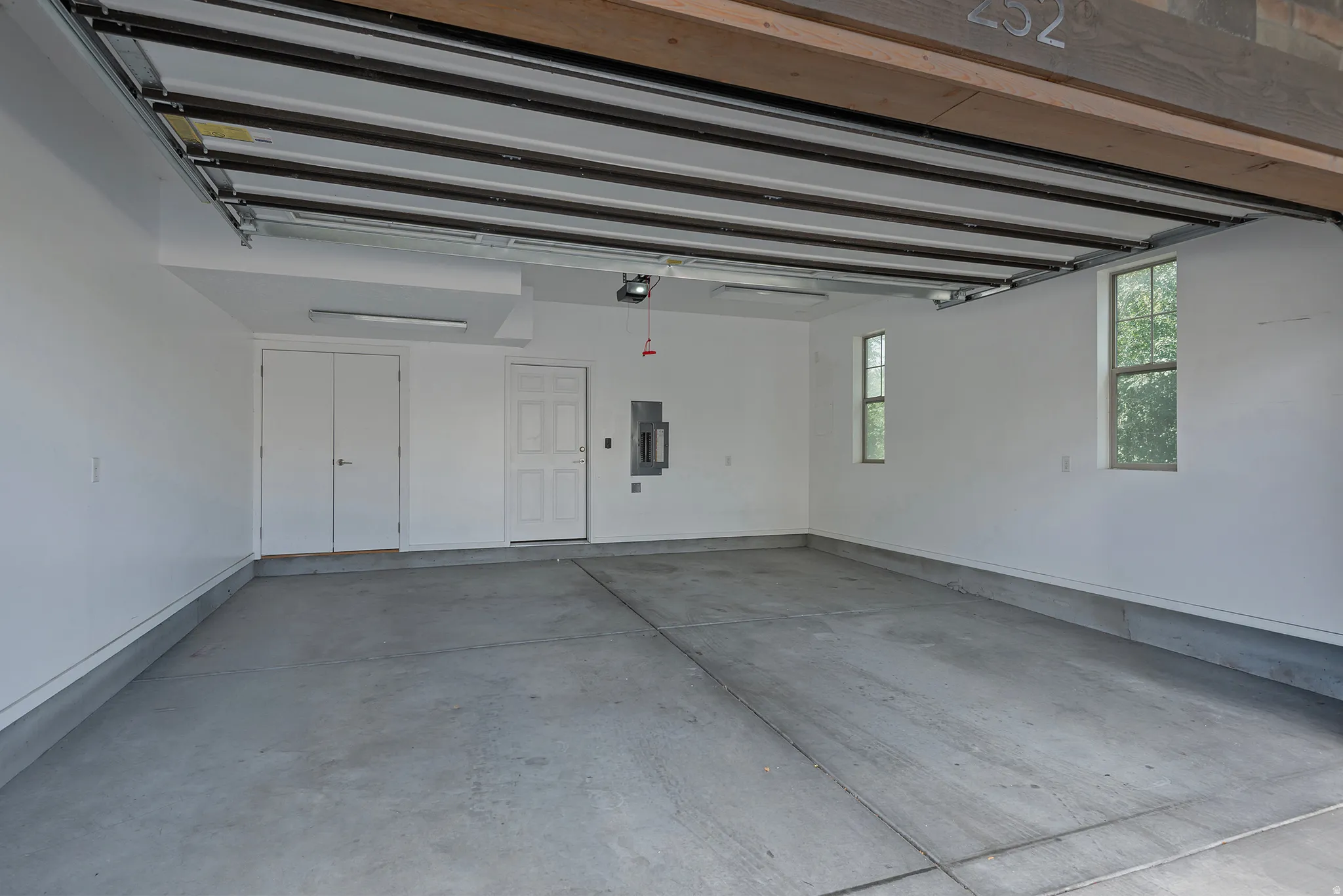 Spacious garage with concrete flooring, two windows, and overhead lighting