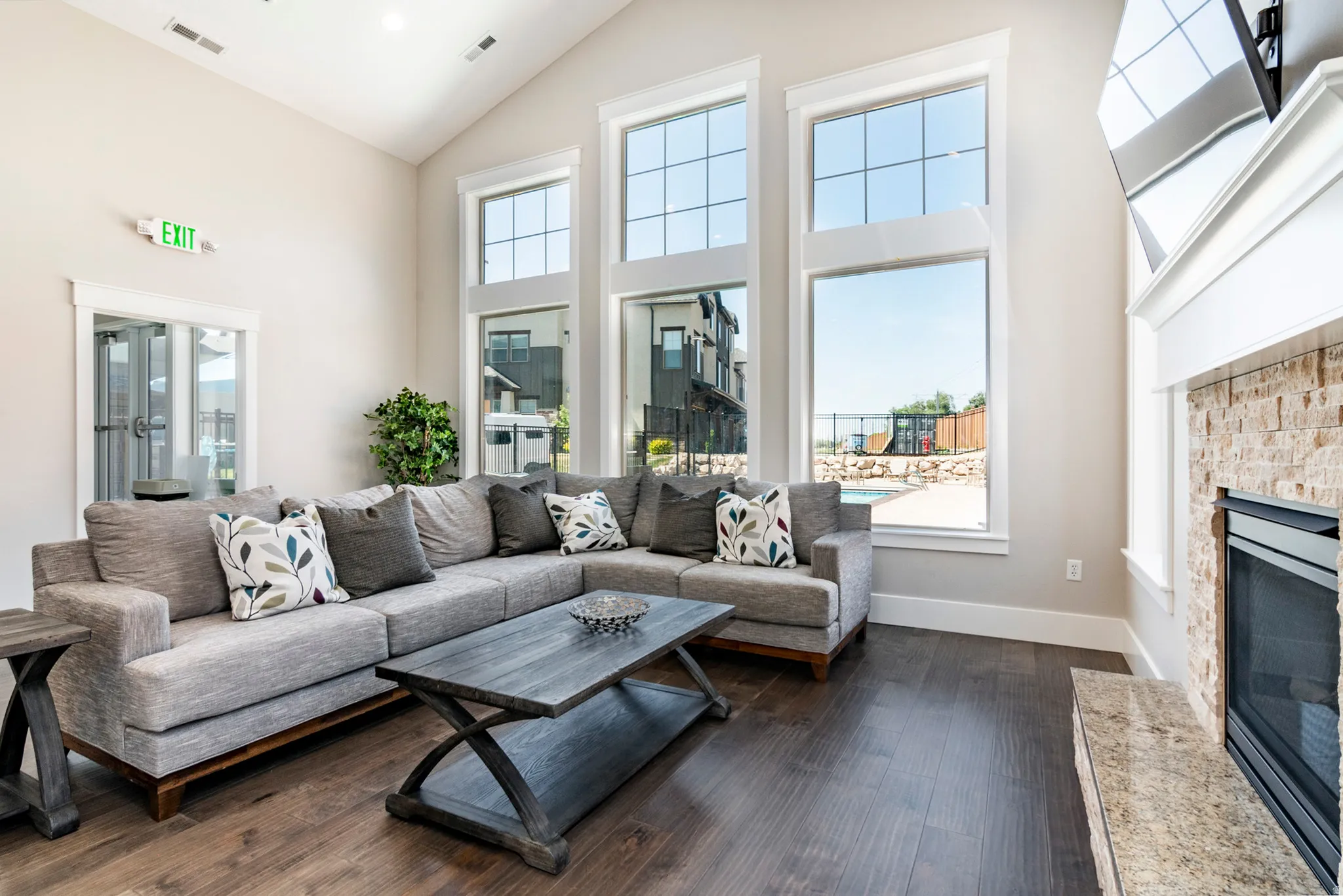 Vaulted ceiling, wood-finish flooring, three large windows, stone-clad fireplace with mantel, and a built-in firebox