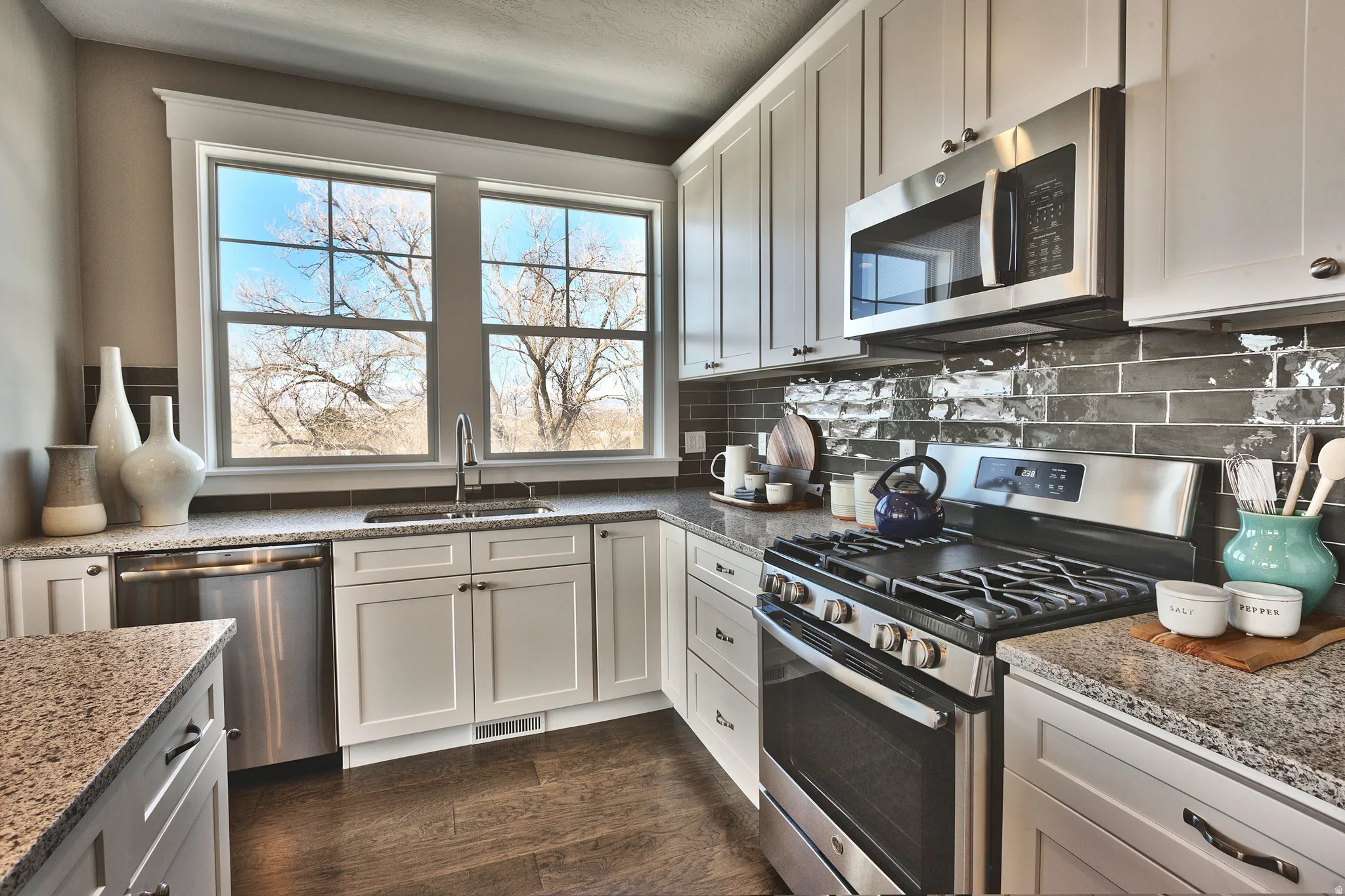 Kitchen featuring white cabinetry, stainless steel appliances, granite countertops, a subway tile backsplash, and wood-finish flooring