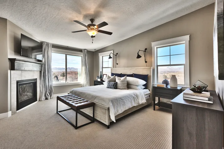 Primary Bedroom, Recessed fireplace with tile surround, ceiling fan with integrated lighting, large windows, and carpet flooring