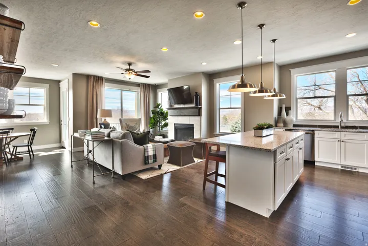 Open-concept living space featuring wood-finish flooring, a kitchen island with seating, a built-in fireplace, and recessed lighting