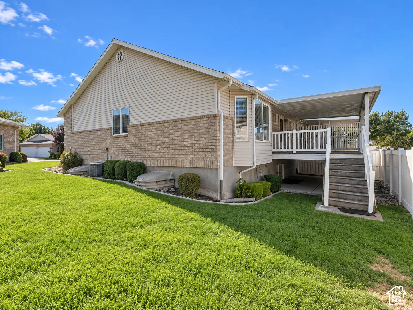 Exterior featuring beige brick and siding, a covered deck with white railing, and a fenced yard