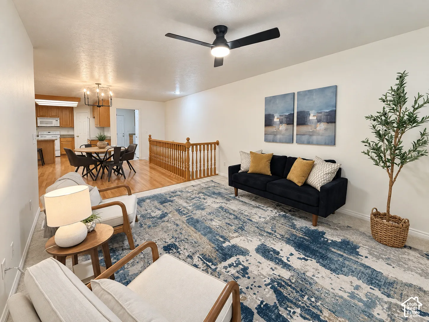 Light-filled living area featuring a ceiling fan, wall-to-wall carpeting, and wood flooring in the dining area