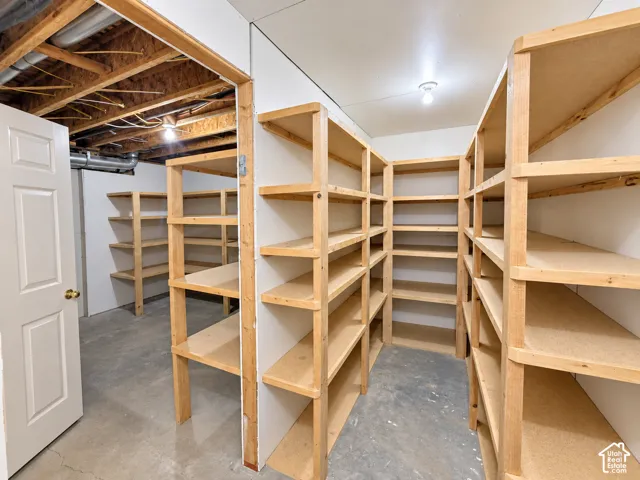 Extensive built-in shelving, concrete flooring, and exposed ceiling joists