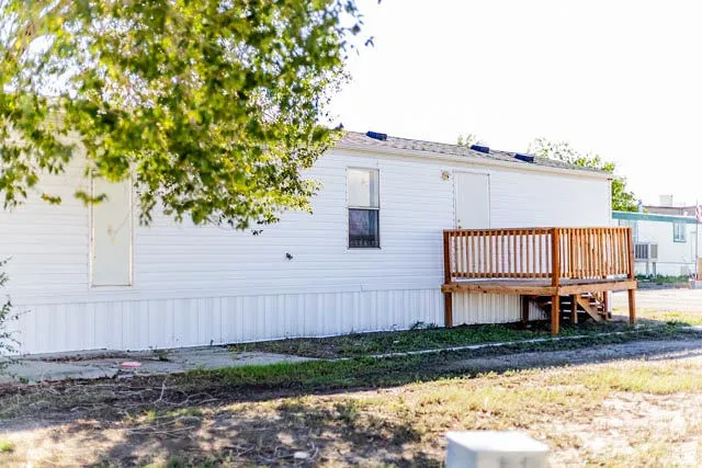 White siding exterior with a wood deck and railing