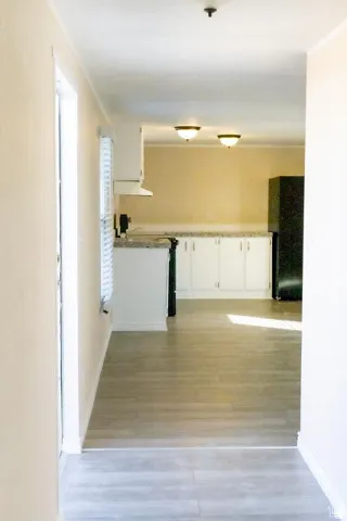 Wood-finish flooring, white cabinetry, integrated range hood, and wall-mounted lighting fixtures