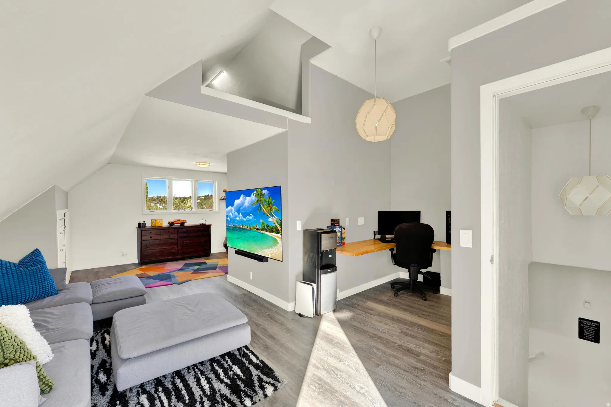 Angled ceiling lines with recessed lighting, wood-finish flooring, corner built-in desk, and multiple windows