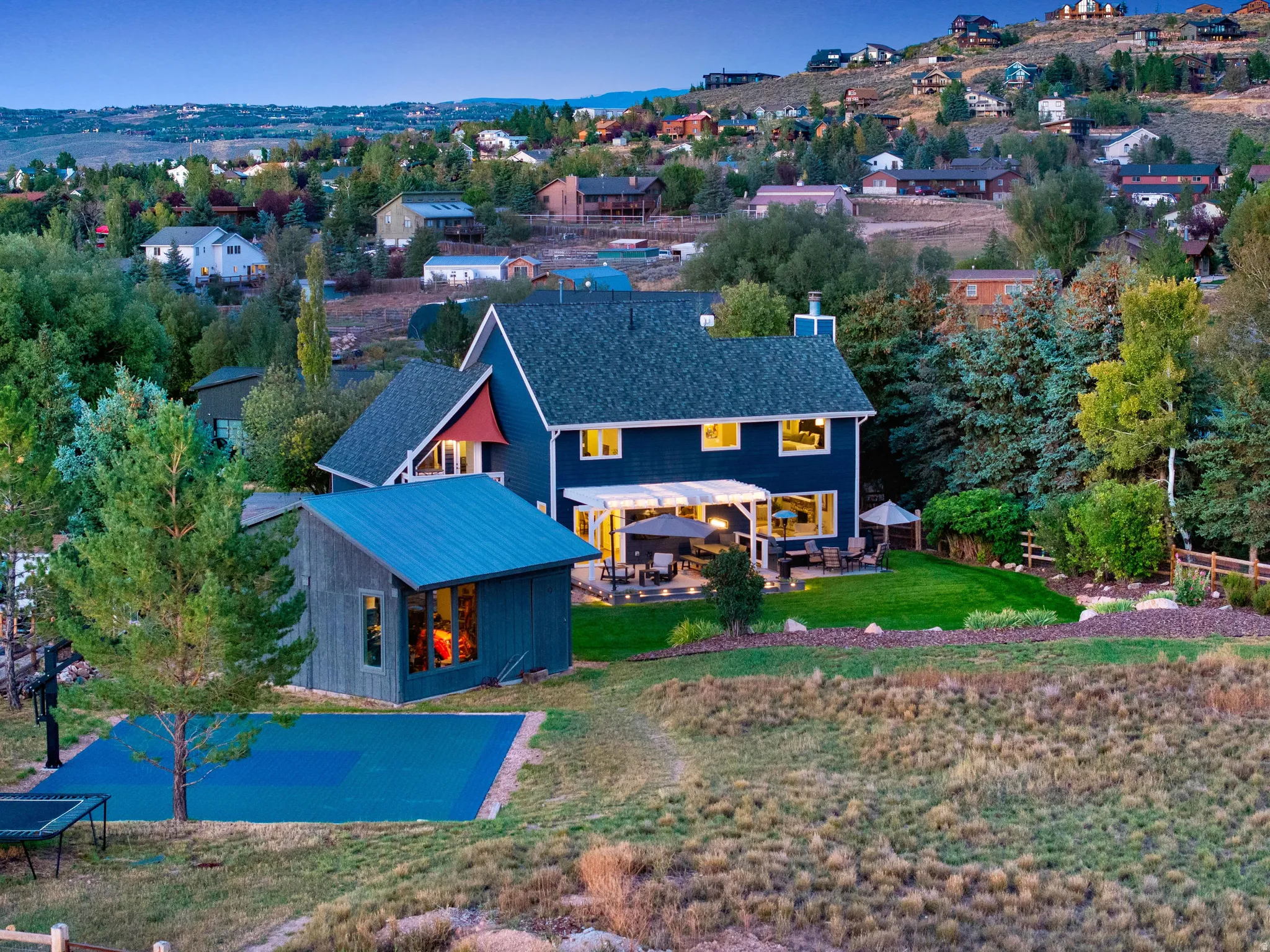 Blue exterior with white trim, covered patio, attached deck, landscaped lawn, and separate outbuilding