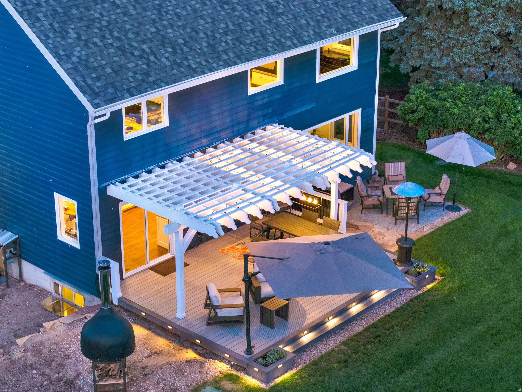 Expansive tiered deck featuring integrated lighting and a white pergola