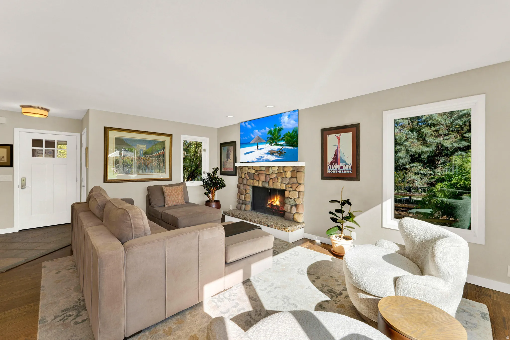 Living area featuring a stone-clad fireplace, recessed lighting, and large windows