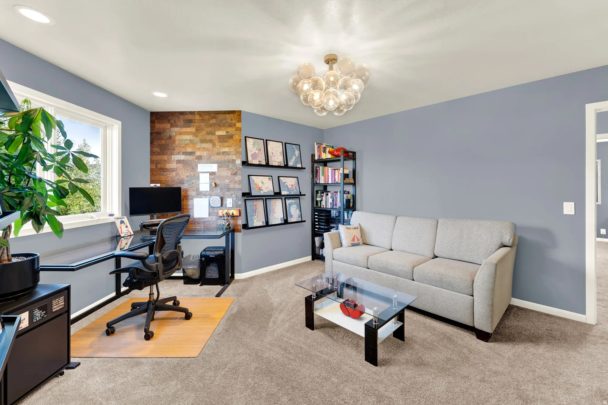 Window with exterior scenery, feature wall with stone-look finish, built-in shelving, ceiling-mounted light fixture, and neutral-toned carpeting