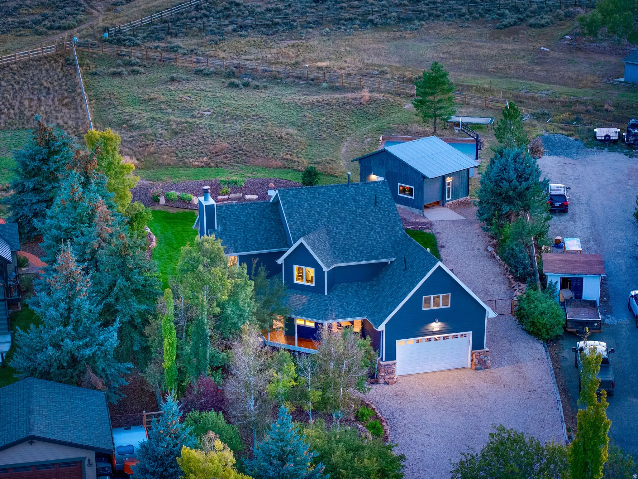 Main residence with attached garage, separate accessory dwelling unit, extensive gravel driveway, and mature landscaping