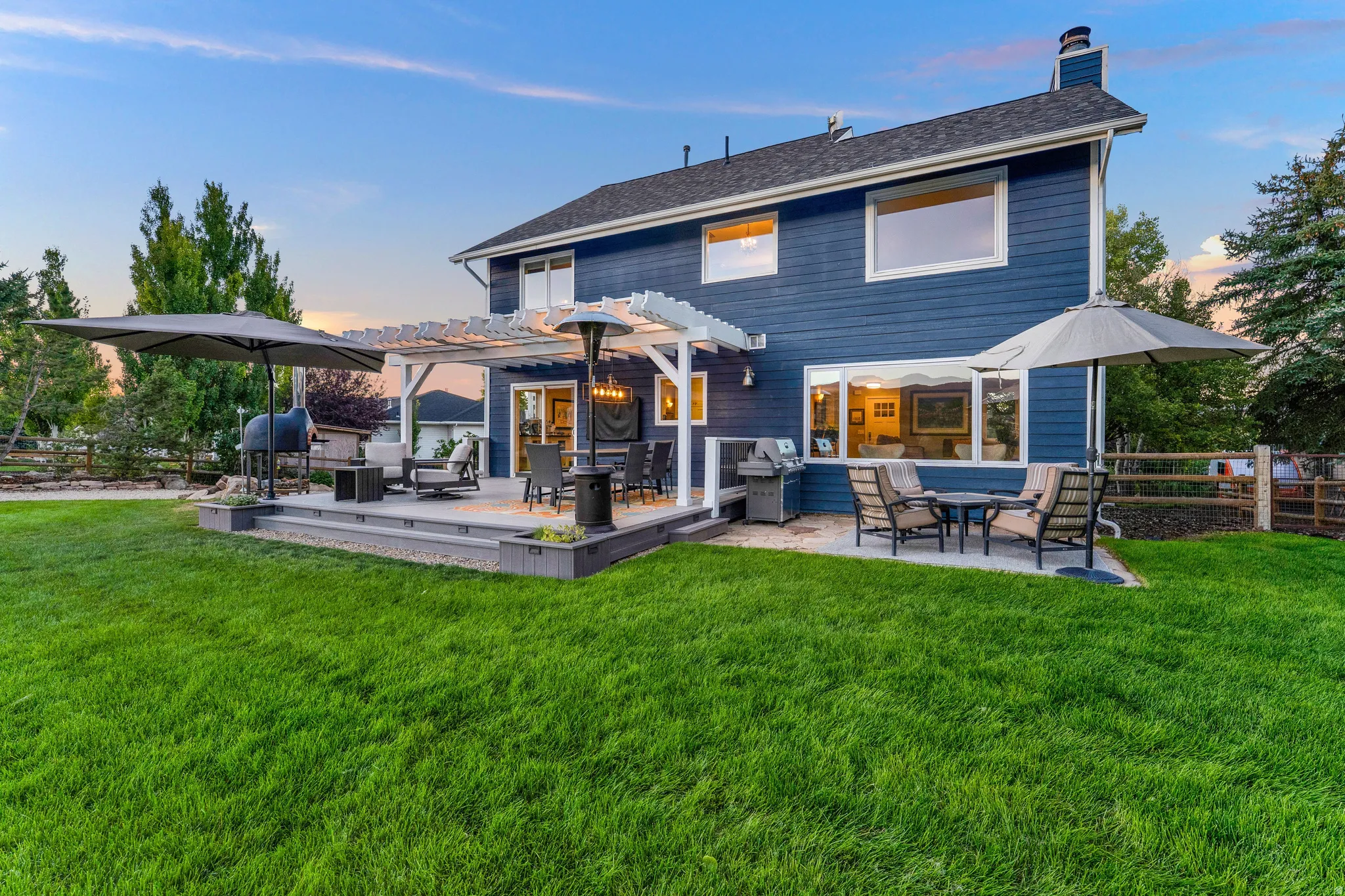 Expansive backyard featuring a multi-level deck, white pergola, and a stone patio