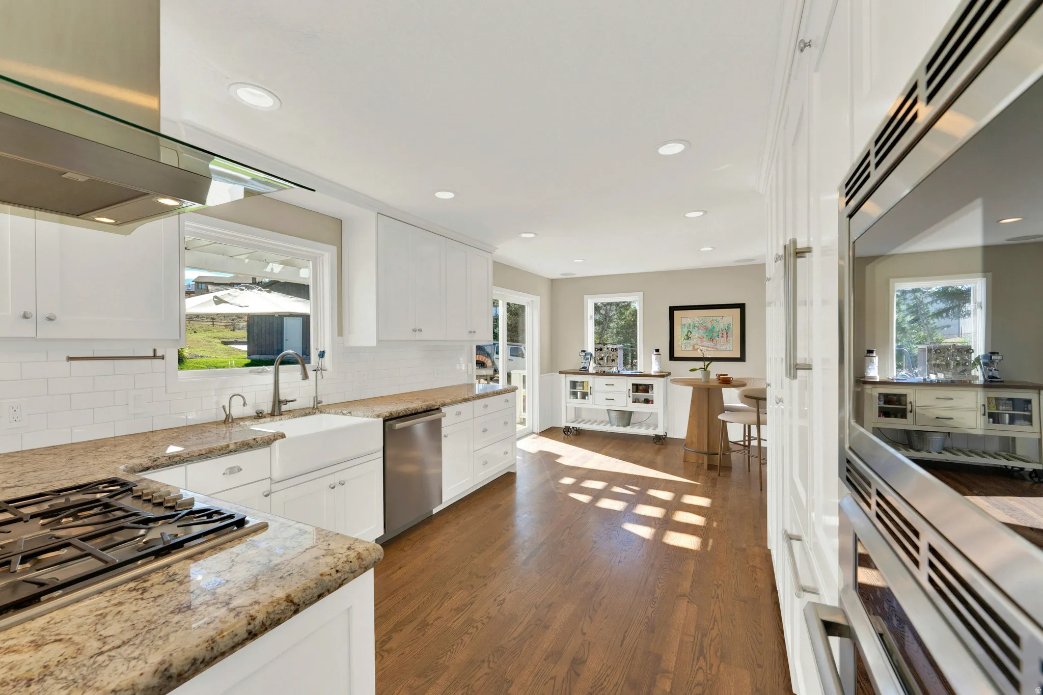 White cabinetry with a farmhouse sink, stainless steel appliances, and recessed lighting