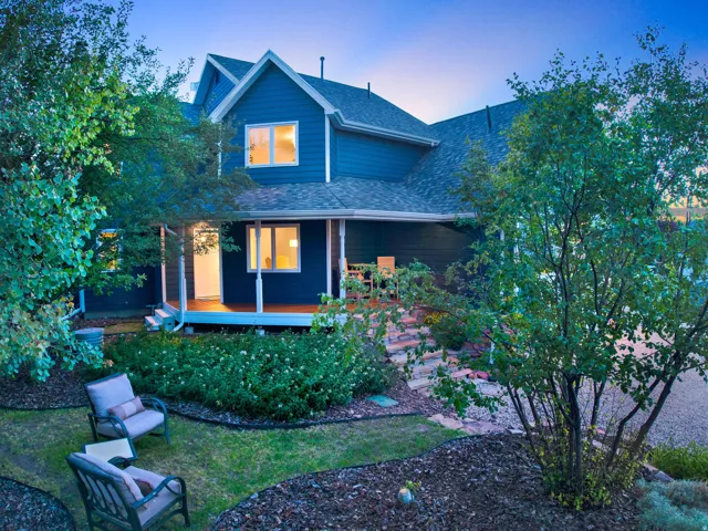 Blue exterior siding, gable roofline, covered porch with columns, stone steps, and landscaped grounds