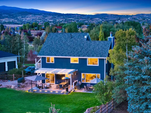 Expansive backyard featuring a green lawn, multi-level patio with an open-slat pergola, and mature trees