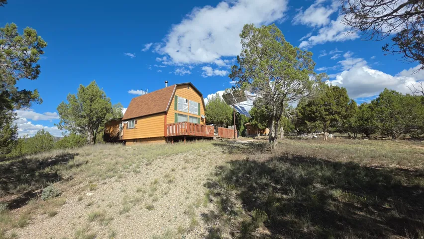 Gabled roof residence featuring a raised wooden deck, orange siding, and a prominent chimney