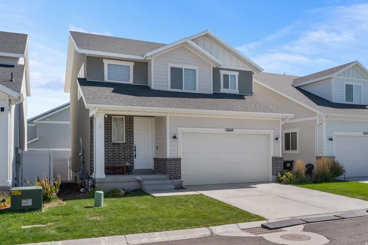 Two-story residence featuring a covered entry, attached garage, and a combination of siding and brick veneer exterior
