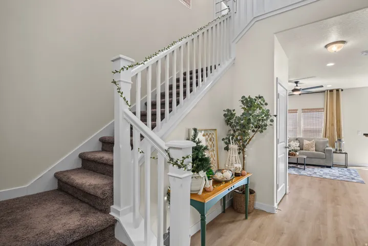 Carpeted staircase with white balusters, wood-finish flooring, and a recessed ceiling light