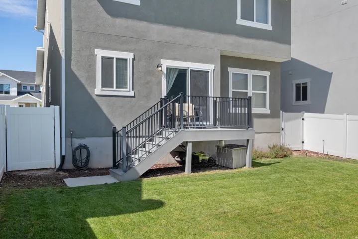 Expansive backyard featuring a manicured lawn, dedicated patio space, and white privacy fencing