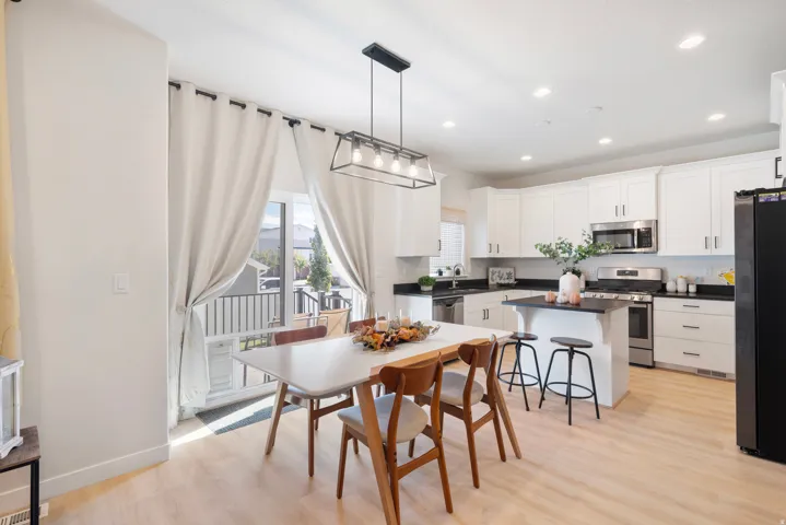 White cabinetry with stainless steel appliances, dark countertops, and a central island with bar seating