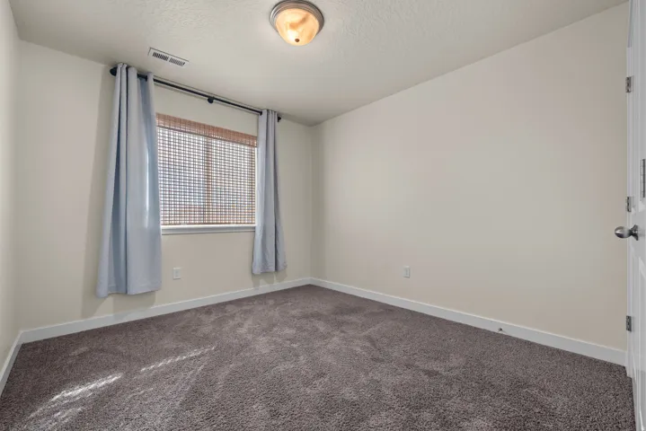 Neutral wall color, carpeted flooring, window with blinds, and flush mount ceiling light
