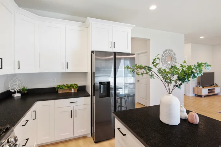 White shaker-style cabinetry with matte black hardware, dark countertops, and stainless steel French door refrigerator