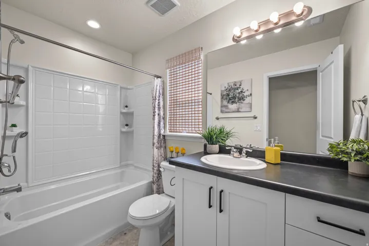 Bathroom featuring a white vanity with black hardware, a dark countertop, and a single basin sink