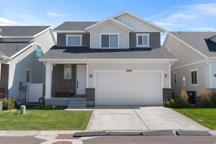 Two-story residence featuring a two-car garage, concrete driveway, and front lawn