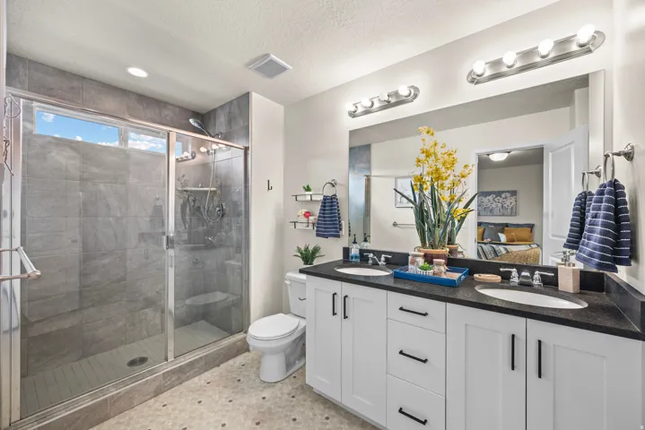 Dual sink vanity with dark countertops, white cabinetry, and matte black hardware