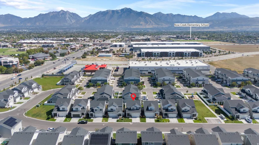 Contemporary neighborhood with a mountain backdrop, featuring a street grid, residential homes, and commercial buildings