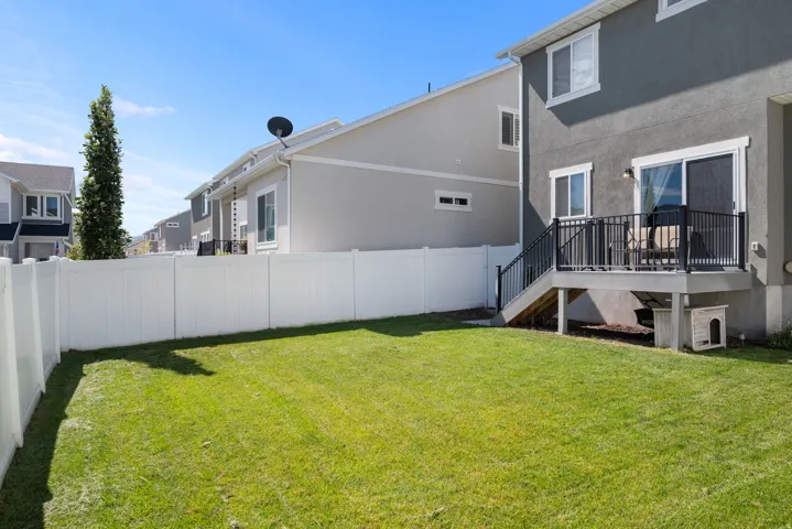 Expansive grassy lawn with a white privacy fence