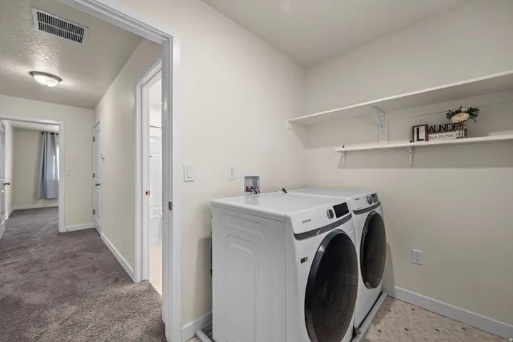 Laundry area with white shelving, light-toned walls, and mosaic-style floor tiles