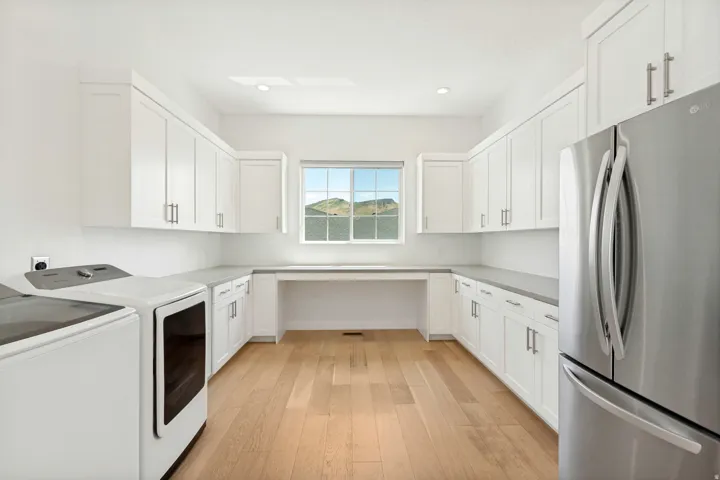 Wood-finish flooring, white shaker-style cabinetry, and light-toned countertops